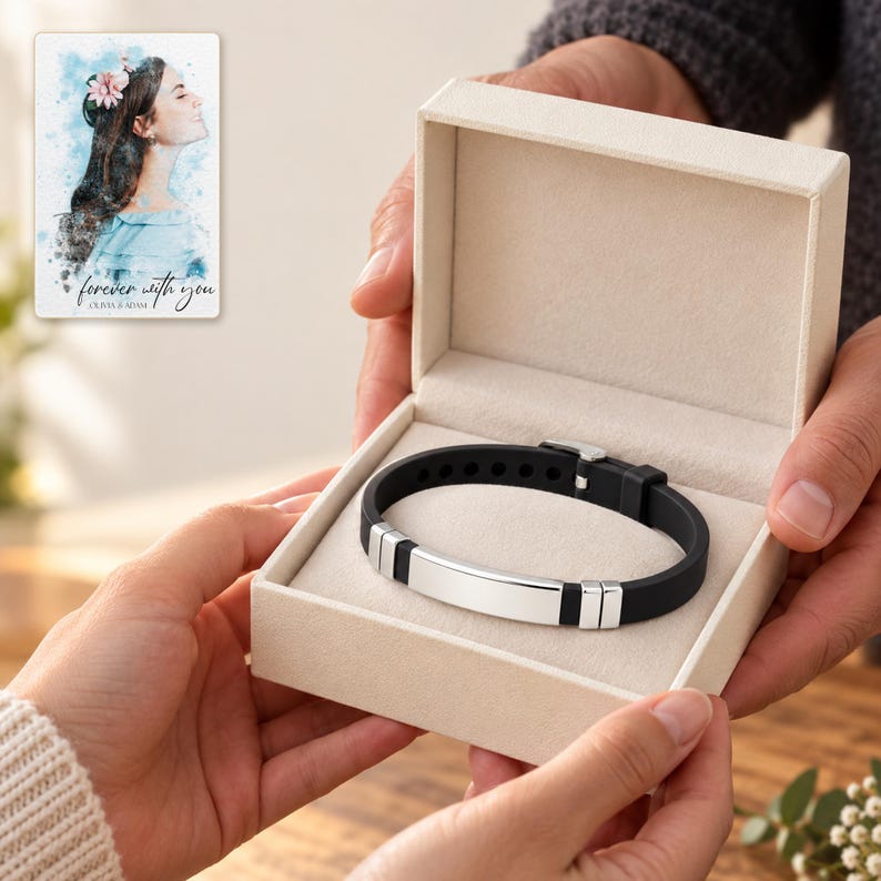 Two adults passing an open ivory jewelry box containing the black strap and silver-tone bar bracelet. A personalized digital greeting card is shown alongside.
