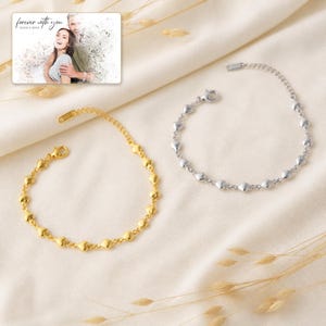 May include: Two heart-link bracelets, one gold-toned and one silver-toned, featuring a lobster clasp. A rectangular card displays a photograph of a couple with the text "forever with you" and "OLIVIA & ADAM" printed in a script font above the image.