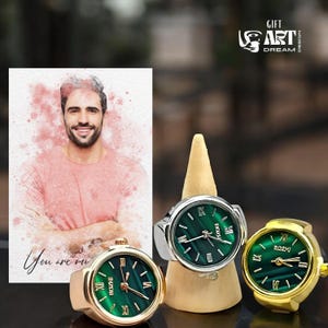 Peut inclure: Trois bagues-montres avec des cadrans verts et des chiffres romains. Une bague-montre a un bracelet dor&eacute;, une autre un bracelet argent&eacute; et une autre est dor&eacute;e. Un portrait &agrave; l'aquarelle d'un homme est en arri&egrave;re-plan, avec le texte "You are me".