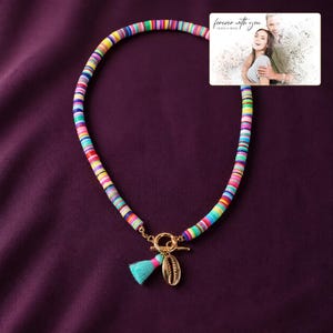 Blue Fiesta Shell Necklace arranged on soft ivory linen in a refined neutral flat lay.