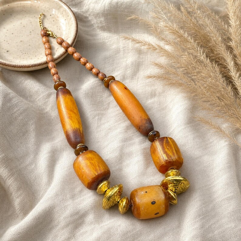 Gift ready presentation of Brown and gold statement beaded necklace in an open jewelry box lined with natural ivory linen