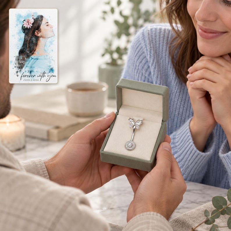 Two adults exchanging an open jewelry box with the butterfly navel bar visible inside. A personalized digital greeting card is shown alongside.