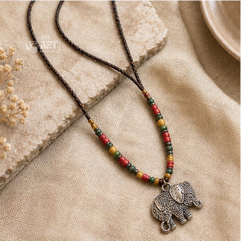 On-model lifestyle photo of long silver tone elephant pendant boho necklace worn with neutral clothing