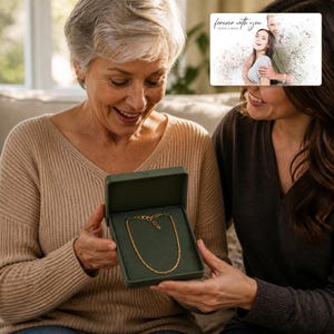 Puede incluir: Un collar de cadena de cuerda en tono dorado con cierre de mosquet&oacute;n, presentado dentro de un joyero rectangular de color verde oliva oscuro. La caja cuenta con un forro interior suave de color verde oscuro que contrasta con el tono dorado.