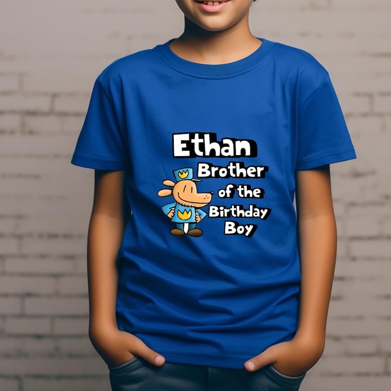 May include: A blue t-shirt with a cartoon dog wearing a hat and the text "Ethan Brother of the Birthday Boy".