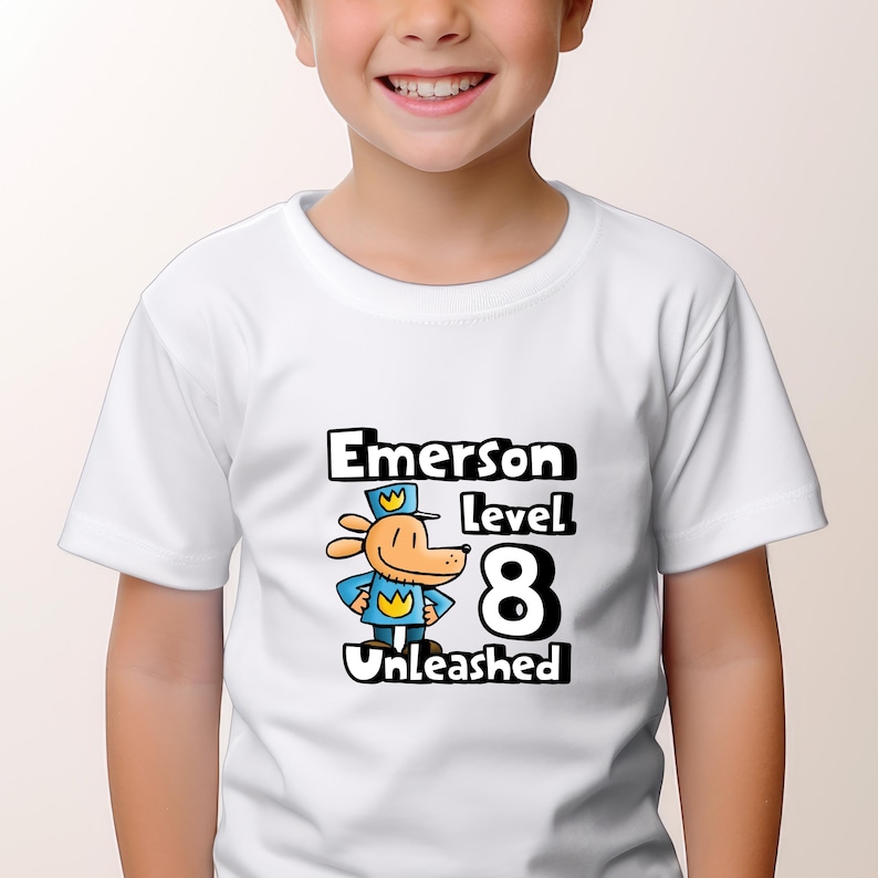 May include: White t-shirt with a cartoon dog wearing a blue hat and the text "Emerson level 8 Unleashed".