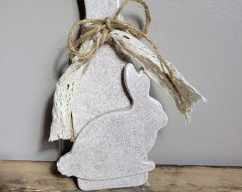 May include: A white ceramic bunny shaped cutting board with a rustic twine bow and lace trim.