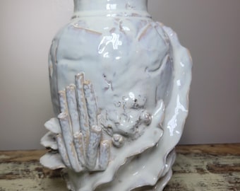May include: A white ceramic vase with a textured surface and a sculpted coral reef design. The vase has a wide base and a narrow neck. The coral reef design includes various shapes and textures, adding visual interest. The vase is approximately 12 inches tall.