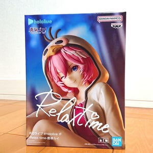 以下が含まれることがあります： ピンクの髪と青い目のキャラクターのフィギュアが描かれた箱。白い鳥のようなデザインのパーカーを着ています。「hololive」と「Relax time」の文字が英語と日本語で書かれています。