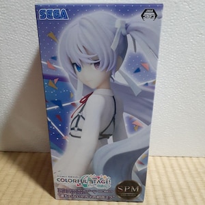 May include: A white and blue box with a colorful design. The box features a figure of a young woman with long white hair, wearing a white shirt and a black and white skirt. The box also features the text "Project SEKAI COLORFUL STAGE!" and "SPM"