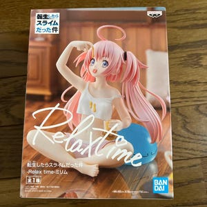 以下が含まれることがあります： ピンク色の髪で天使の輪をつけたキャラクターのフィギュアの箱。白いクロップド丈のトップスとピンクのショートパンツを着用し、青いスライムの隣に座っている。箱には「Relax time」および「転生したらスライムだった件」という文字が記載されている。