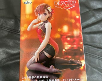 以下が含まれることがあります： Taito Desktop Cuteの製品ボックス。短い茶色の髪で、白い花のヘアアクセサリーを付けた赤と黒のチャイナドレス風の衣装を着たアニメスタイルのフィギュアが描かれています。ボックスにはDesktop Cuteの文字が記載されています。