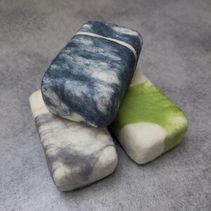 May include: Three rectangular bars of soap, each with a different color pattern. The top bar is blue and white, the middle bar is gray and white, and the bottom bar is green and white.