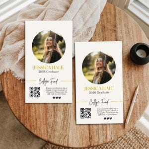 May include: Two graduation announcement cards with a photo of a smiling graduate in a cap and gown. The cards have the text "JESSICA HALE 2026 Graduate College Fund" and a QR code. The cards are on a wooden surface.