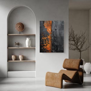 Peut inclure: Tableau abstrait avec un design textur&eacute; aux tons noirs, orange et gris. L'&oelig;uvre est expos&eacute;e dans un espace de vie moderne avec une chaise en cuir marron et des &eacute;tag&egrave;res d&eacute;coratives.