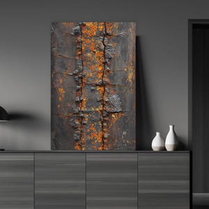 May include: Abstract art print featuring a close-up of a weathered, rusty metal surface. The artwork displays a textured, dark gray background with vertical orange and brown streaks, and visible cracks. The piece is mounted on a dark gray cabinet.