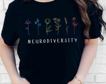 May include: Black t-shirt with a floral design in various colors and the word "NEURODIVERSITY" in white. The flowers are in shades of purple, blue, green, yellow, and red. The shirt is made of a soft material.