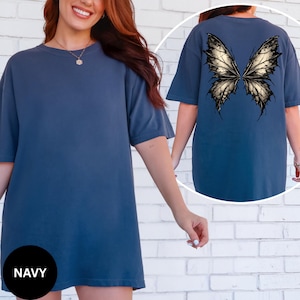 May include: Navy blue short-sleeved t-shirt with a large butterfly wing design on the back. The wings are detailed with black and gold accents. The word "NAVY" is printed on a black circle at the bottom.