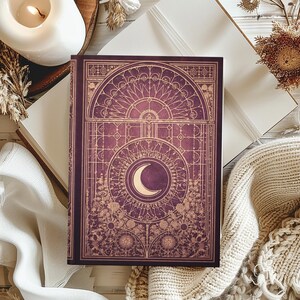 Peut inclure: Un journal violet avec un motif de croissant de lune doré et des motifs floraux. La couverture présente un motif de vitrail orné. Le journal est ouvert sur une surface blanche, avec une bougie allumée et une couverture en tricot en arrière-plan.