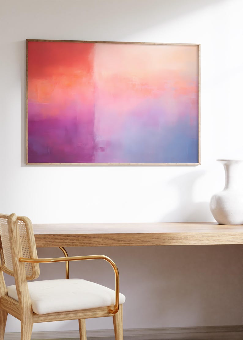 May include: Abstract painting in a wooden frame with a pink, orange, and blue color scheme. The painting is hanging on a white wall above a wooden desk and chair.
