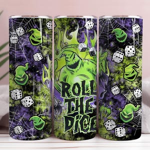 Könnte beinhalten: Drei Edelstahlbecher mit einem gruseligen Design. Das Design zeigt eine grüne Figur, Würfel, Spinnweben und den Text "Roll the Dice" in Schwarz und Grün. Der Hintergrund ist eine Mischung aus Lila und Schwarz.