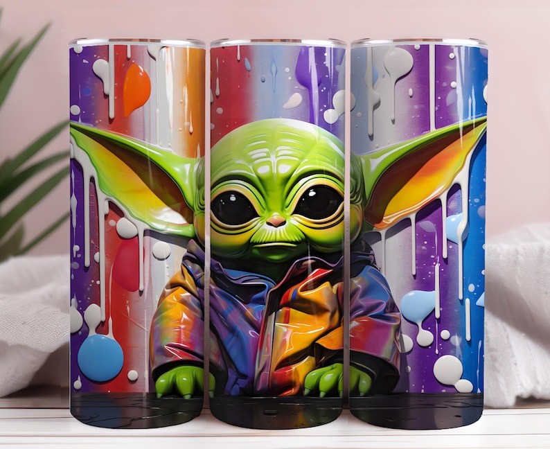 May include: Three cylindrical tumblers with a colourful design of a green alien character. The artwork features paint drips and a rainbow background. The tumblers are designed to hold liquids and are suitable for everyday use.