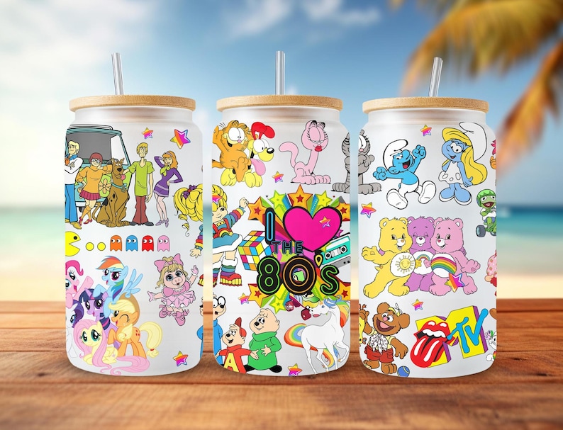 May include: Three white tumblers with bamboo lids and straws. Each tumbler features a different 80s cartoon theme:  Scooby Doo, Care Bears, and Smurfs. The tumblers are decorated with colorful cartoon characters and the text "I Love the 80s".