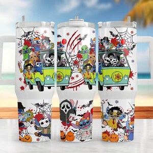 May include: White tumbler with a Halloween-themed design. The design features a green van with cartoon characters, spiderwebs, bats, and pumpkins. The tumbler has a handle and a straw.