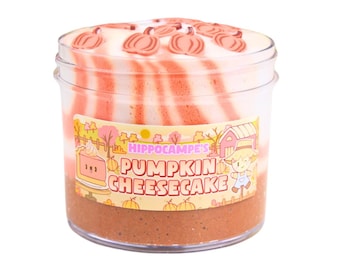 May include: A clear plastic jar filled with a layered, pink and white slime with a brown bottom layer. The jar has a label that reads "Hippocampe's Pumpkin Cheesecake".