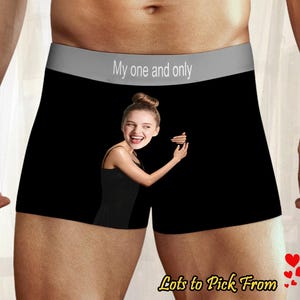 Może przedstawiać: Czarne bokserki z szarą talią z napisem "My one and only". Bokserki mają grafikę kobiety w czarnej sukience. W prawym dolnym rogu znajduje się napis "Lots to Pick From" z grafiką serca.
