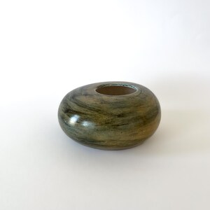 Könnte beinhalten: Eine handgefertigte, ovale Keramikvase mit breiter Öffnung. Die Vase hat einen Marmoreffekt mit Grüntönen, Braun und Beige. Der Innenraum ist hellbeige. Ein dekorativer Artikel.