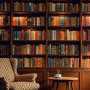 May include: A brown leather armchair with a patterned fabric seat and back sits in front of a large wooden bookcase filled with books. A small table with a cup of coffee sits in front of the chair. The bookcase has a warm, inviting atmosphere.