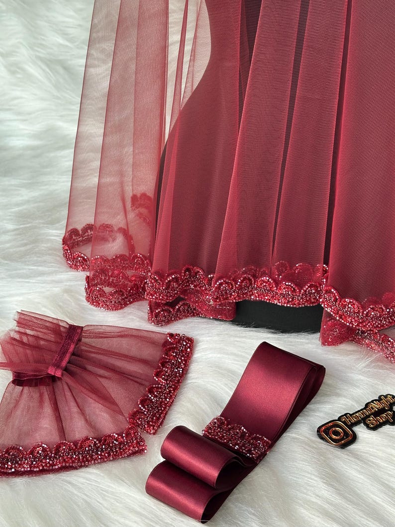 Pu&ograve; includere: Velo da sposa color borgogna con bordino perlato, fascia in raso color borgogna abbinata con bordino perlato e un paio di maniche in tulle color borgogna con bordino perlato.