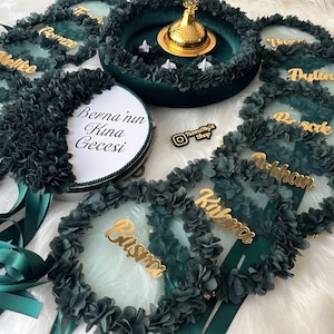 There are green bridesmaid tambourines and a bride tambourine with text. frame made by laser cut flowers and some satin tails. green henna basket