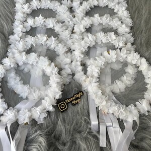 There are white bridesmaid tambourines frame made by laser cut flowers and some satin tails