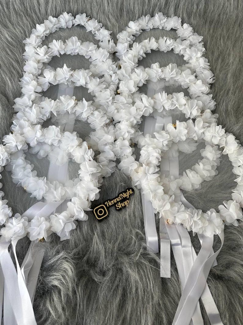 There are white bridesmaid tambourines frame made by laser cut flowers and some satin tails