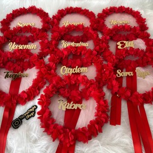There are red bridesmaid tambourines with golden text. frame made by laser cut flowers and some satin tails