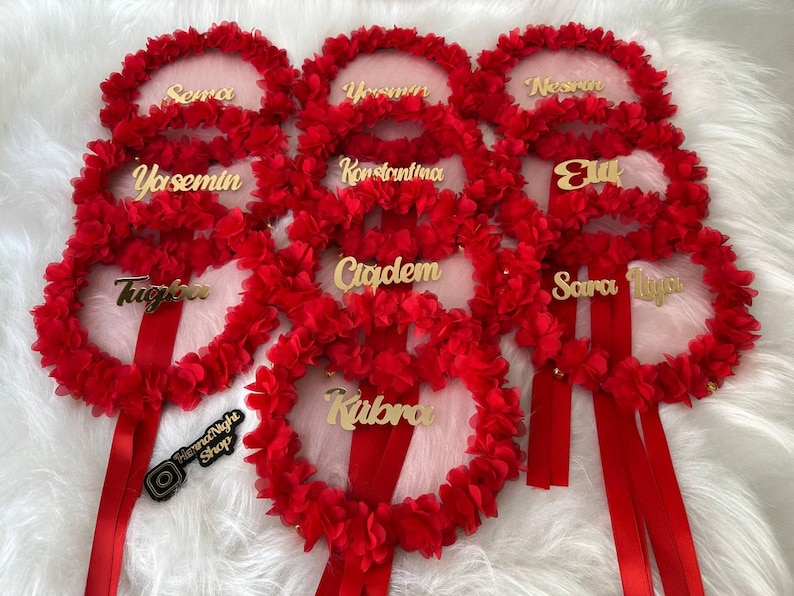 There are red bridesmaid tambourines with golden text. frame made by laser cut flowers and some satin tails