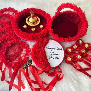 There are red bridesmaid tambourines, bride tsmbourine and henna tray henna basket frame made by laser cut flowers and some satin tails