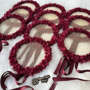 There are red bridesmaid tambourines.l. frame made by laser cut flowers and some satin tails