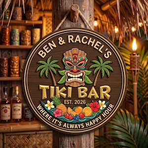 Puede incluir: Un letrero redondo de madera con un gráfico central de máscara tiki, dos palmeras e ilustraciones de frutas tropicales. El texto dice BEN & RACHEL'S TIKI BAR EST. 2026 WHERE IT'S ALWAYS HAPPY HOUR. El letrero cuelga de una cuerda.