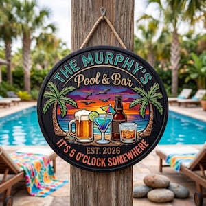 Op de afbeelding: Een rond zwart houten bord met de tekst "THE MURPHY'S Pool & Bar" en "IT'S 5 O'CLOCK SOMEWHERE EST. 2026". Het bord toont een strandscène met drankjes en palmbomen. Het hangt aan een houten paal met een touw.