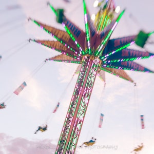 May include: A carnival ride with colorful lights and people swinging in the air. The ride is called "Sky Flyer".