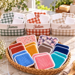 Può includere: Tre cestini in tessuto quadrati con motivi a quadretti vichy in verde, arancione e beige, ciascuno ricamato con i nomi James, Julien e Aurélia. Un vassoio intrecciato contiene una collezione di cuscinetti in tessuto quadrati e testurizzati in vari colori solidi e stampe floreali.