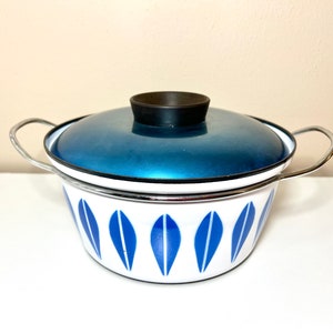 May include: A white enamel pot with a blue and white leaf pattern and a blue enamel lid with a black knob. The pot has two silver handles.
