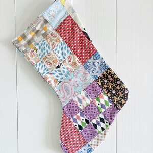 May include: A patchwork Christmas stocking with a variety of colorful fabrics, including pink, blue, purple, and yellow.
