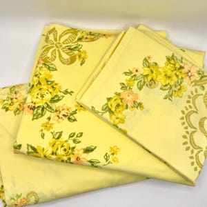 May include: Yellow floral bed sheets with a matching pillowcase. The sheets feature a repeating pattern of yellow and peach roses with green leaves. The pillowcase has a floral design on the corner.