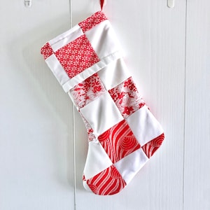 May include: A white and red patchwork Christmas stocking with a variety of patterns.