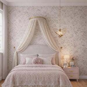 Könnte beinhalten: Ein Schlafzimmer mit einem Bett mit einer rosafarbenen, gesteppten Tagesdecke und weißer Spitzenborte. Das Bett hat einen Baldachin mit cremefarbenen Spitzengardinen. Ein rosa Nachttisch mit Schmetterlingsknöpfen und eine schmetterlingsförmige Leuchte vervollständigen die Einrichtung.