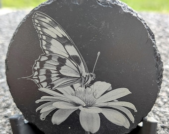 Posavasos circular de pizarra con grabado láser de una majestuosa mariposa sobre una flor, original de ForgedIN3DStudio